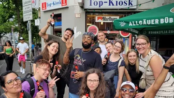 Group of people holding drinks outside a kiosk.