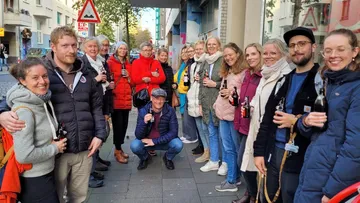 Group of people posing with drinks on a street.