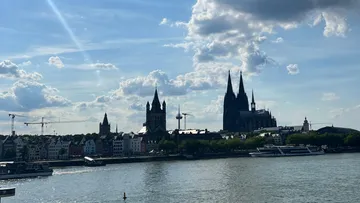 Skyline with cathedral, river, and cloudy sky.