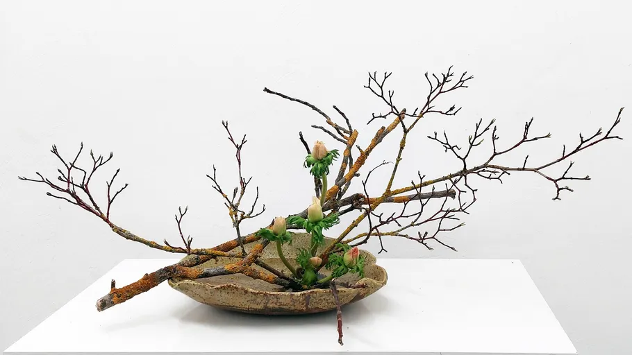 Kompliziertes Ikebana-Arrangement mit Zweigen und Blumen.