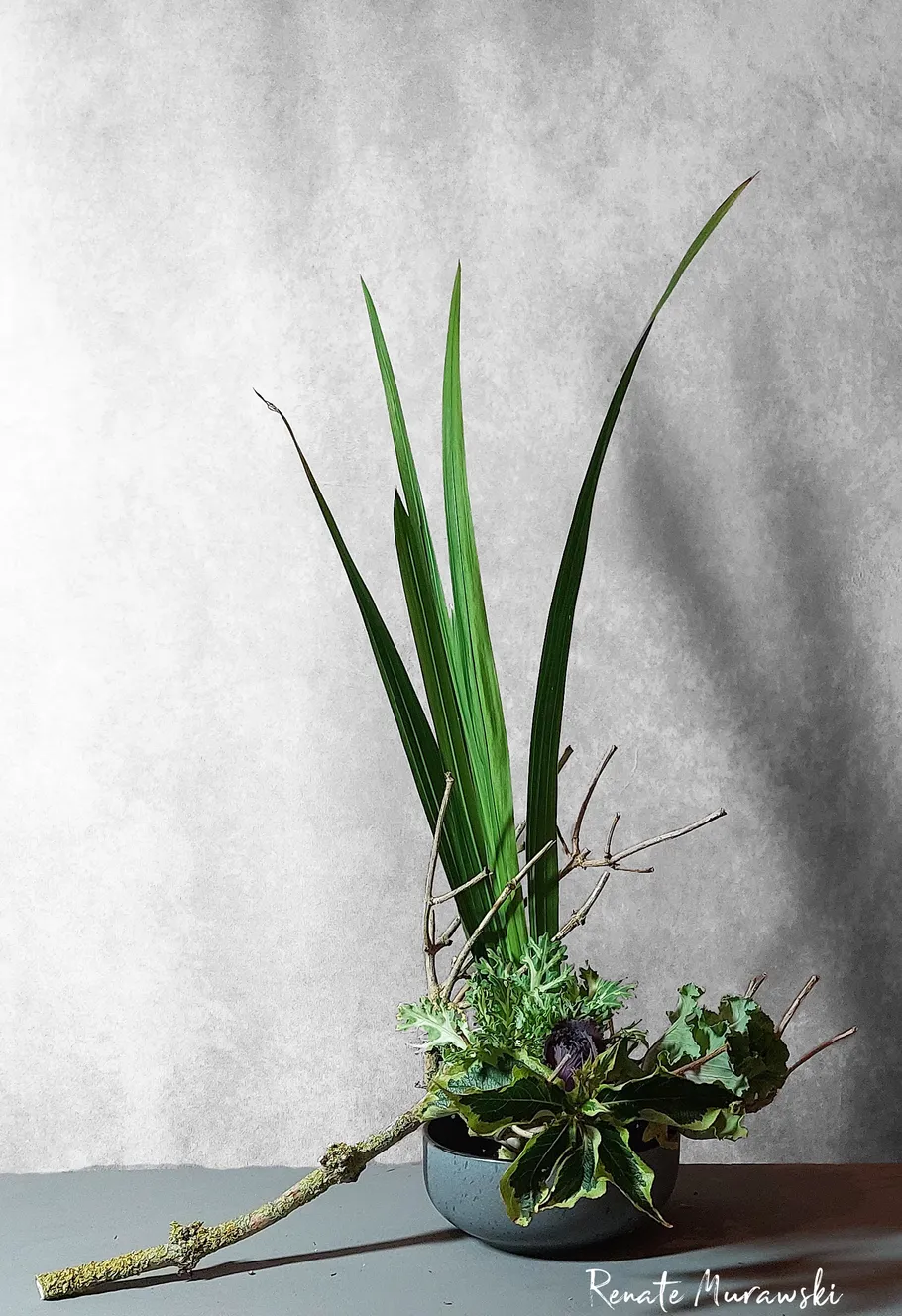 Flower arrangement with leaves and branches in a bowl.