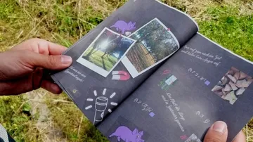 Person, die eine Broschüre mit Fotos von draußen in der Hand hält.