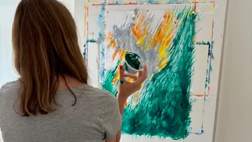 Person painting abstract art on canvas.