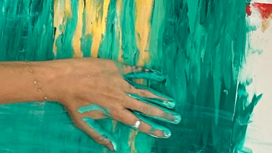 Hand smearing teal paint on canvas.