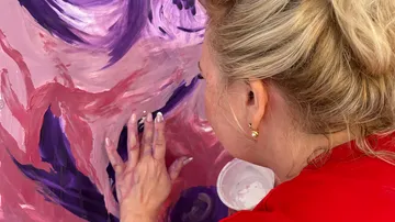Person applying paint to canvas with fingers.