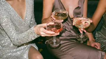 Three women holding champagne glasses in elegant dresses.
