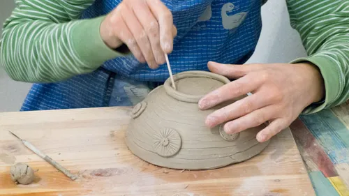Person shaping pottery bowl with hands.