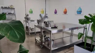 Kitchen with stainless steel tables, mixers, and cupcake art.