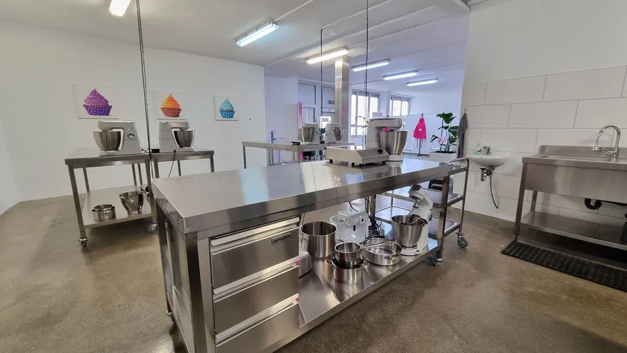 Industrial kitchen with metal counters and mixers.