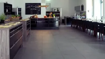 Moderne Küche mit schwarzen Schränken, großem Esstisch.