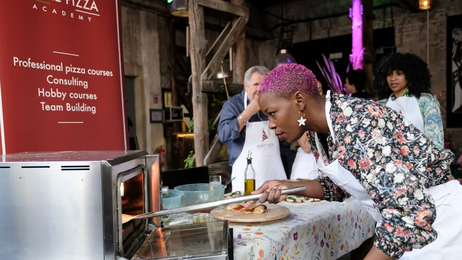 Person putting pizza in oven at cooking class.