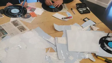 People crafting with vinyl records and paper cutouts.