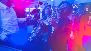 Saxophonist playing at lively indoor party.