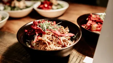 Bowl of shredded meat and vegetables on table.