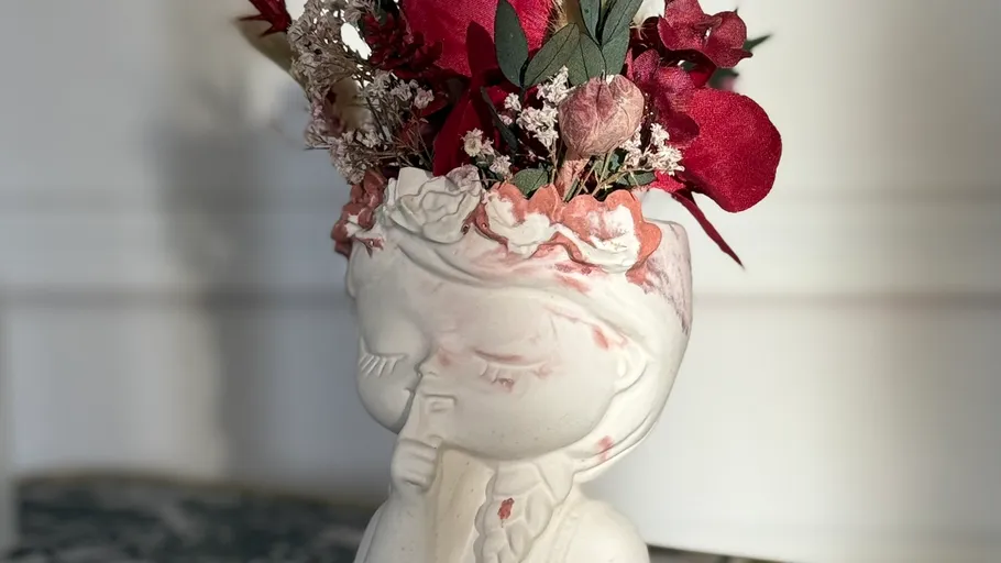 Ceramic planter shaped as head with flowers inside.