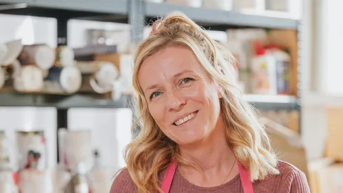 Smiling woman with apron in a workshop.