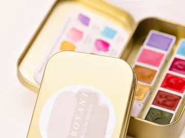 Golden box with watercolors opened, colors visible.