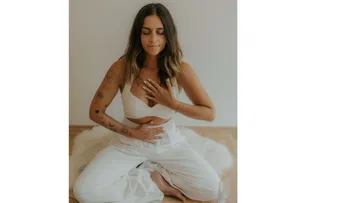 Woman meditating cross-legged on floor.