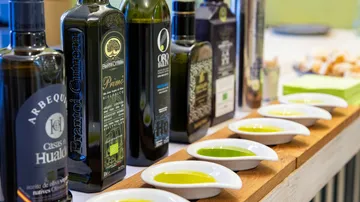 Bottles of olive oil with tasting bowls on table.