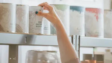 Person selecting paint can from shelf.