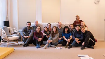 Gruppe von Menschen, die auf dem Boden in einem Raum sitzen.