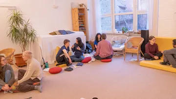 Leute, die auf dem Boden sitzen und drinnen Diskussionen führen.