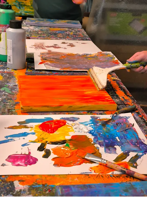 Person using paintbrush on colorful canvas.