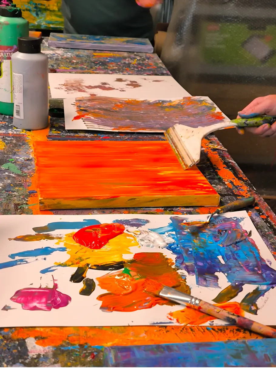Person using paintbrush on colorful canvas.
