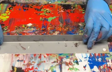 Hände mit Handschuhen, die Farbe auf der Oberfläche verteilen