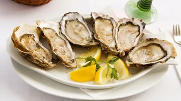 Plate of oysters with lemon slices and parsley.