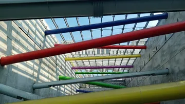 Bunte Rohre hängen diagonal in einem modernen Raum.