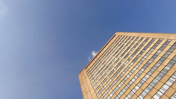 Hochhaus ragt in den blauen Himmel, mit Fensterflächen.