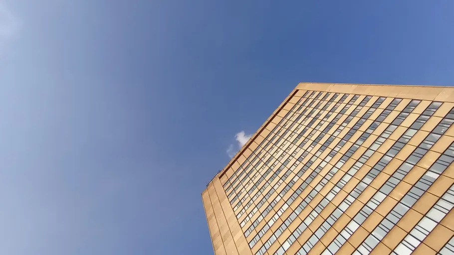 Hochhaus ragt in den blauen Himmel, mit Fensterflächen.