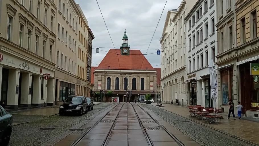 Eisenbahnschienen verlaufen durch eine leere Stadtstraße mit Häusern.