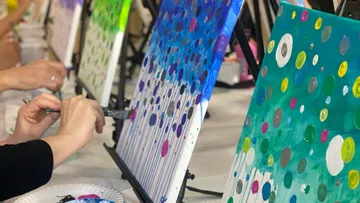 People painting colorful abstract canvases in a studio.