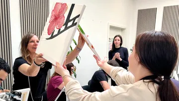 Zwei Personen tauschen Bilder in einem Kunstkurs aus.