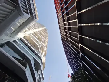 Hohe Gebäude stehen gegenüber, blauer Himmel sichtbar.