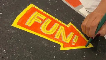 Person, die bunt zeichnet. „LUSTIG!“ unterschreiben