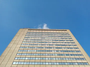 Hochhaus mit vielen Fenstern unter blauem Himmel.