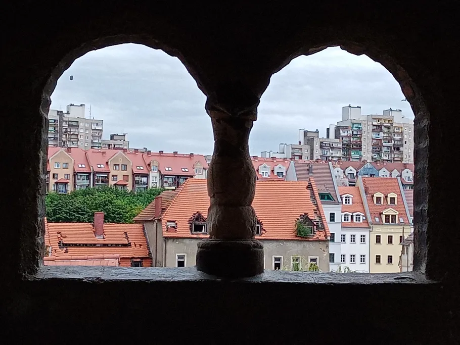 Fensterrahmen mit Blick auf bunte Dächer und Gebäude.