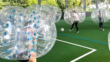 Leute spielen Bubble Soccer auf dem Hallenfeld.