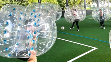 People playing bubble soccer on a field.