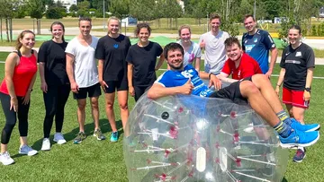 Gruppe von Menschen, die draußen mit einem Seifenblasenball posieren.