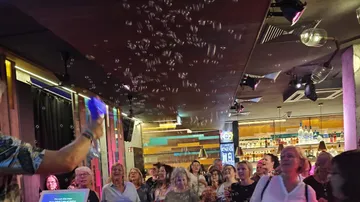 Die Leute schauen sich Seifenblasen bei einer Veranstaltung im Innenbereich an.