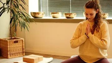 Woman meditating indoors with a peaceful expression.