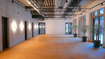 Geräumiges Zimmer im Industriestil mit Wandbeleuchtung.