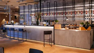 Modern bar with stools and illuminated shelves.