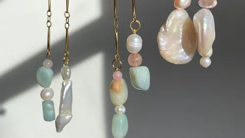 Dangling earrings with pearls and stones on display.