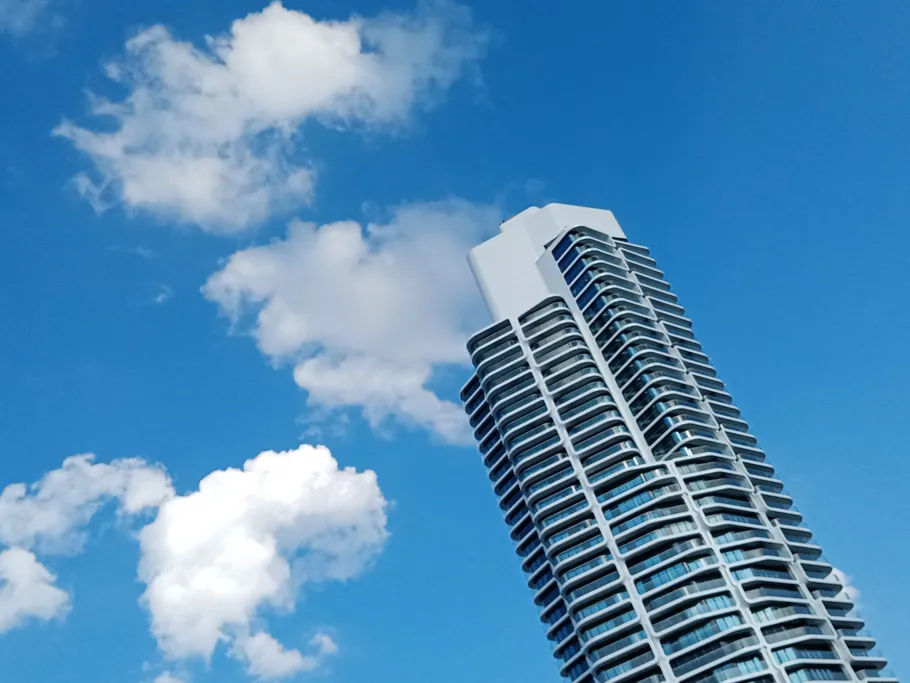 Hochhaus ragt in den blauen Himmel mit Wolken.