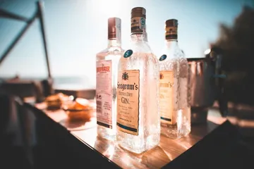 Bottles of gin on outdoor table in sunlight.